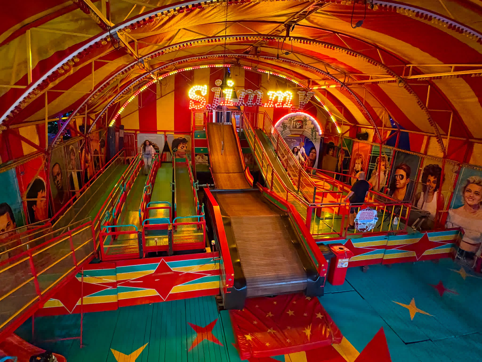Cakewalk Nostalgische cakewalk-attractie Sjimmy met glijbanen, wandelbaan en kermisverlichting onder een rood-gele tent