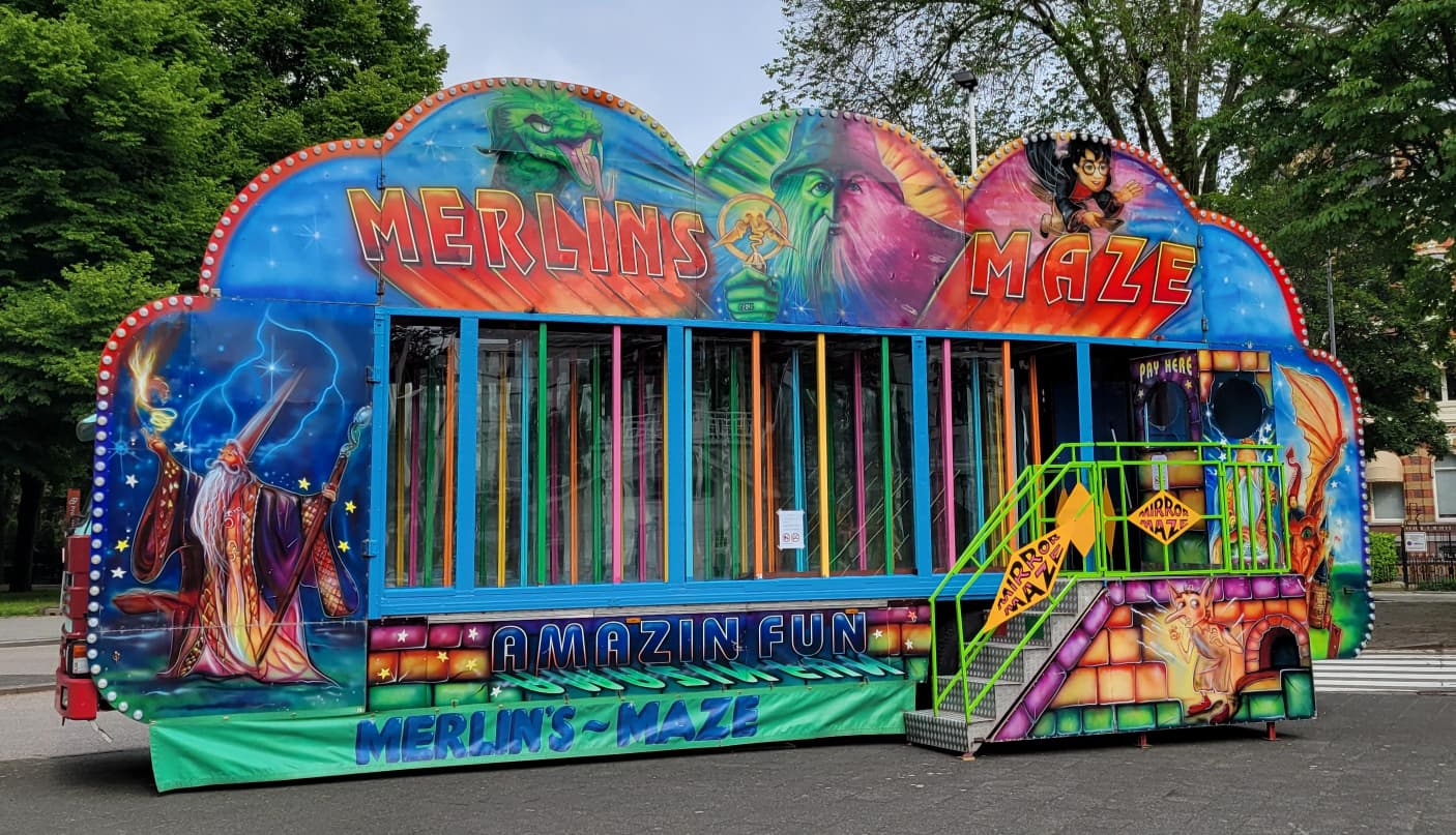 Glazen Doolhof Glazen doolhof Merlin's Maze van Nostalgisch Kermis Collectief, met beschilderde gevel van tovenaar Merlin en trap naar de ingang